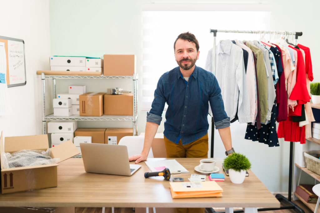 A home-based clothing business owner managing apparel inventory, packaging orders, and running an online fashion store from a well-organized home office.