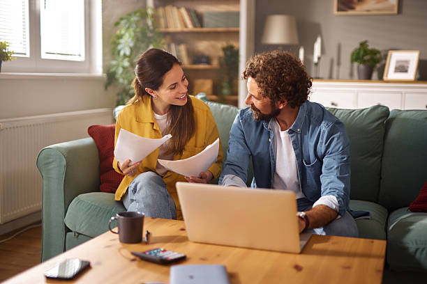 Small business owners reviewing loan documents with a laptop, discussing business financing and the small business loan application process.