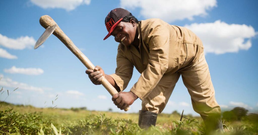 Entrepreneur working in a field with farming tools, representing Kiva microloans and startup funding opportunities for small businesses and agriculture.