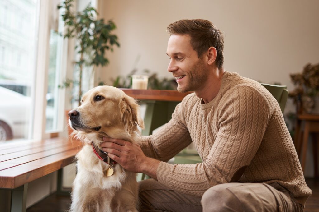 Professional pet sitter caring for a golden retriever indoors, demonstrating trusted in-home pet sitting, companionship, and personalized pet care services.