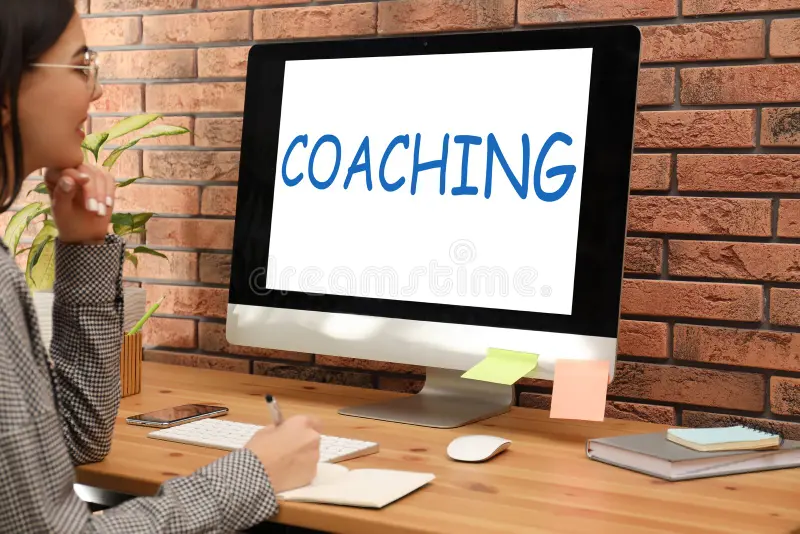 Woman learning about coaching on a computer at home, representing online life coaching and professional development. 