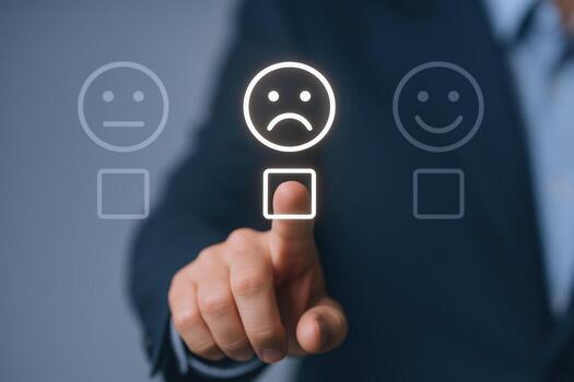 Business customer feedback concept showing a hand selecting a sad face icon to represent negative customer experience. 