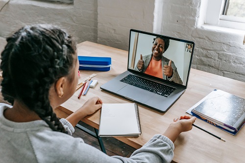 Online tutoring session showing a student learning with a tutor through a laptop video call.