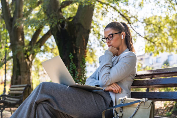 Woman working on a laptop outdoors in a park, representing online life coaching and remote business work.