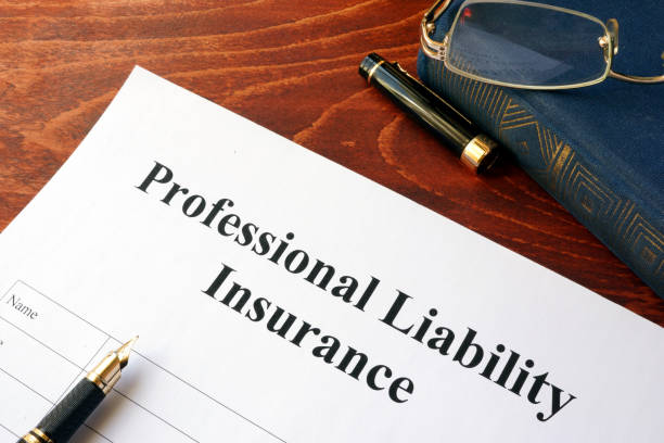 Professional liability insurance document on a wooden desk with a pen, eyeglasses, and book. 