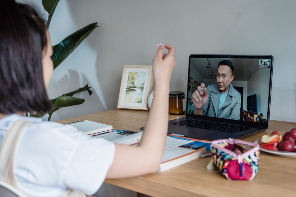 Online tutoring session with a student learning from home through a video call on a laptop.