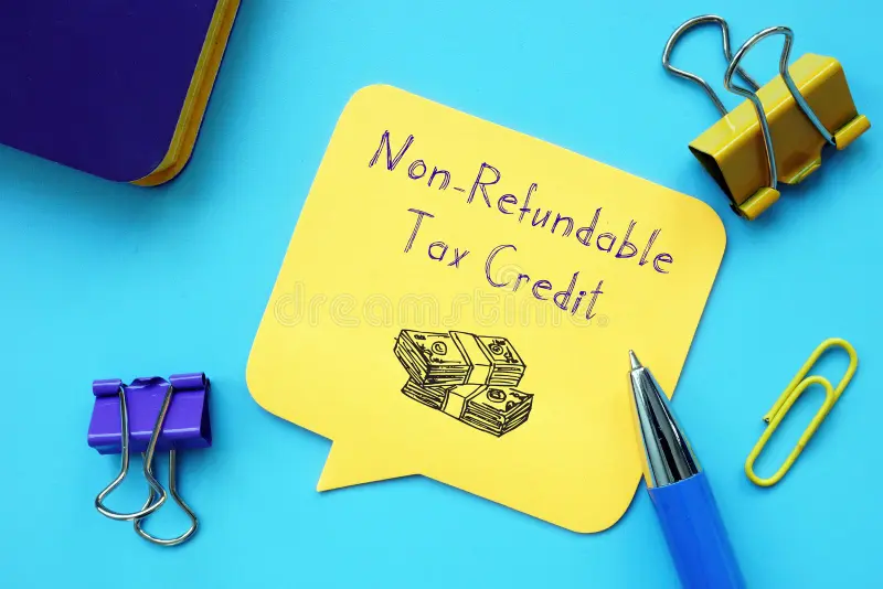A yellow note reading “Non-Refundable Tax Credit” with a money illustration, surrounded by stationery on a blue background.