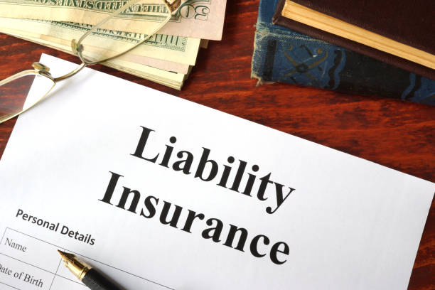 Liability insurance form with a pen, glasses, and cash on a wooden desk